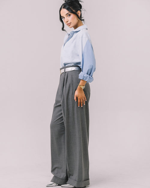 Model wearing the Youmsara Deux Bleu Shirt paired with the Valenza grey wool–silk wide-leg pleated trousers on a studio background.